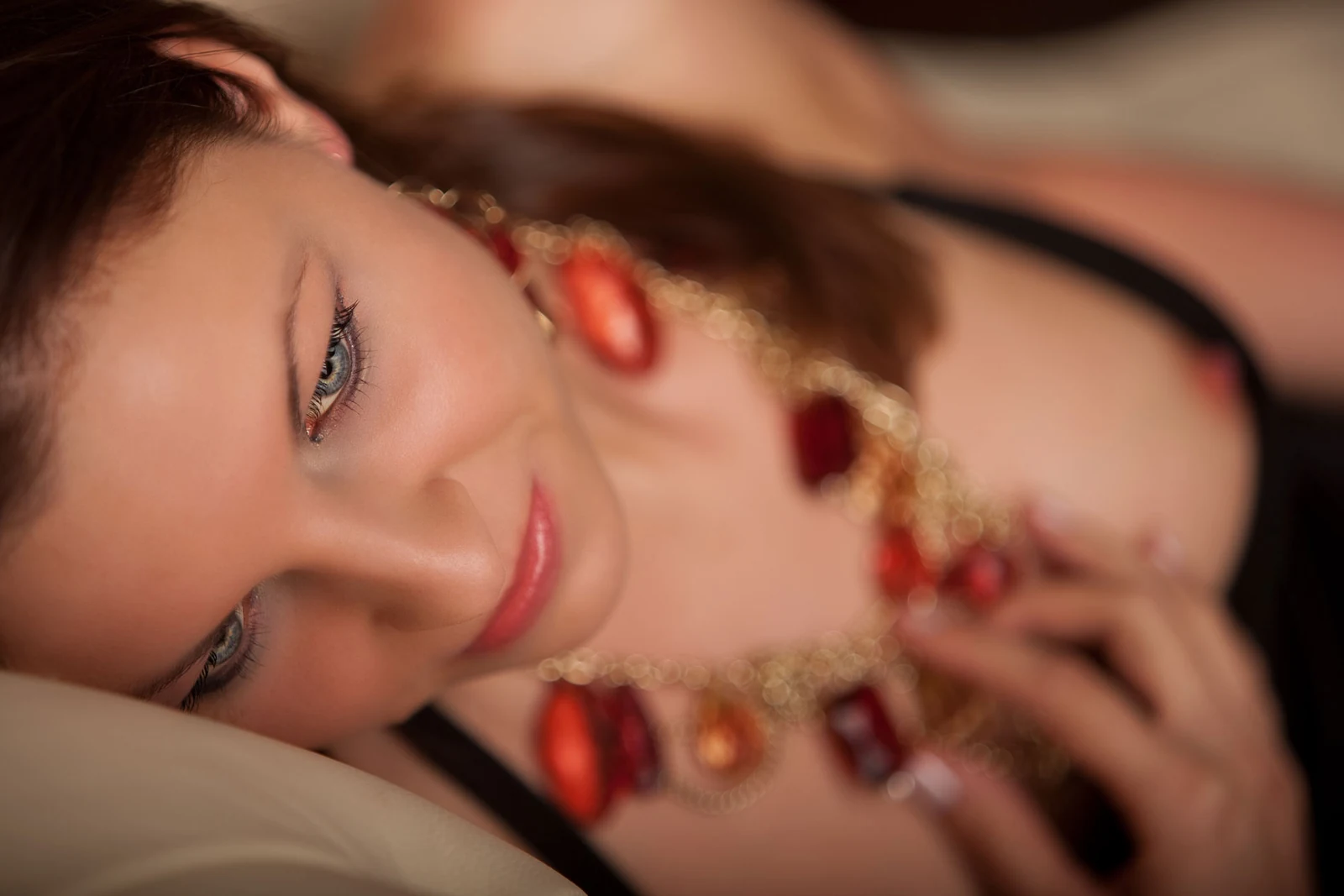 Boudoirportrait einer liegenden Frau mit rotem Schmuck