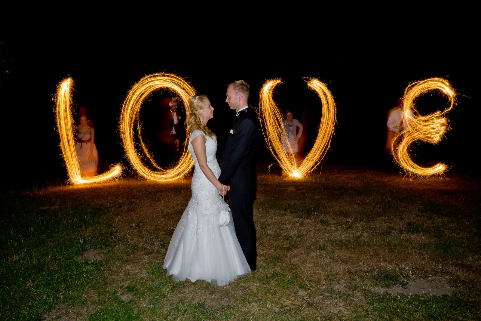 Das Brautpaar vor einem mit Licht geschriebenen LOVE – Hochzeitsreportage von Basti und Debbi