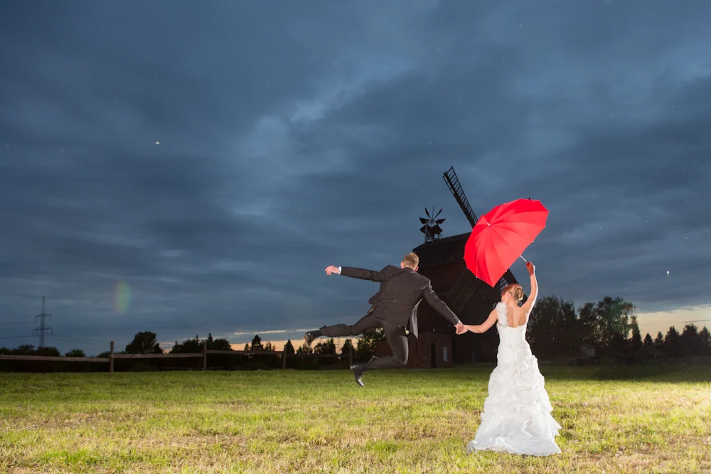 Ein Sprung und ein roter Schirm vor der Windmühle – Hochzeitsreportage von Delf Zeh