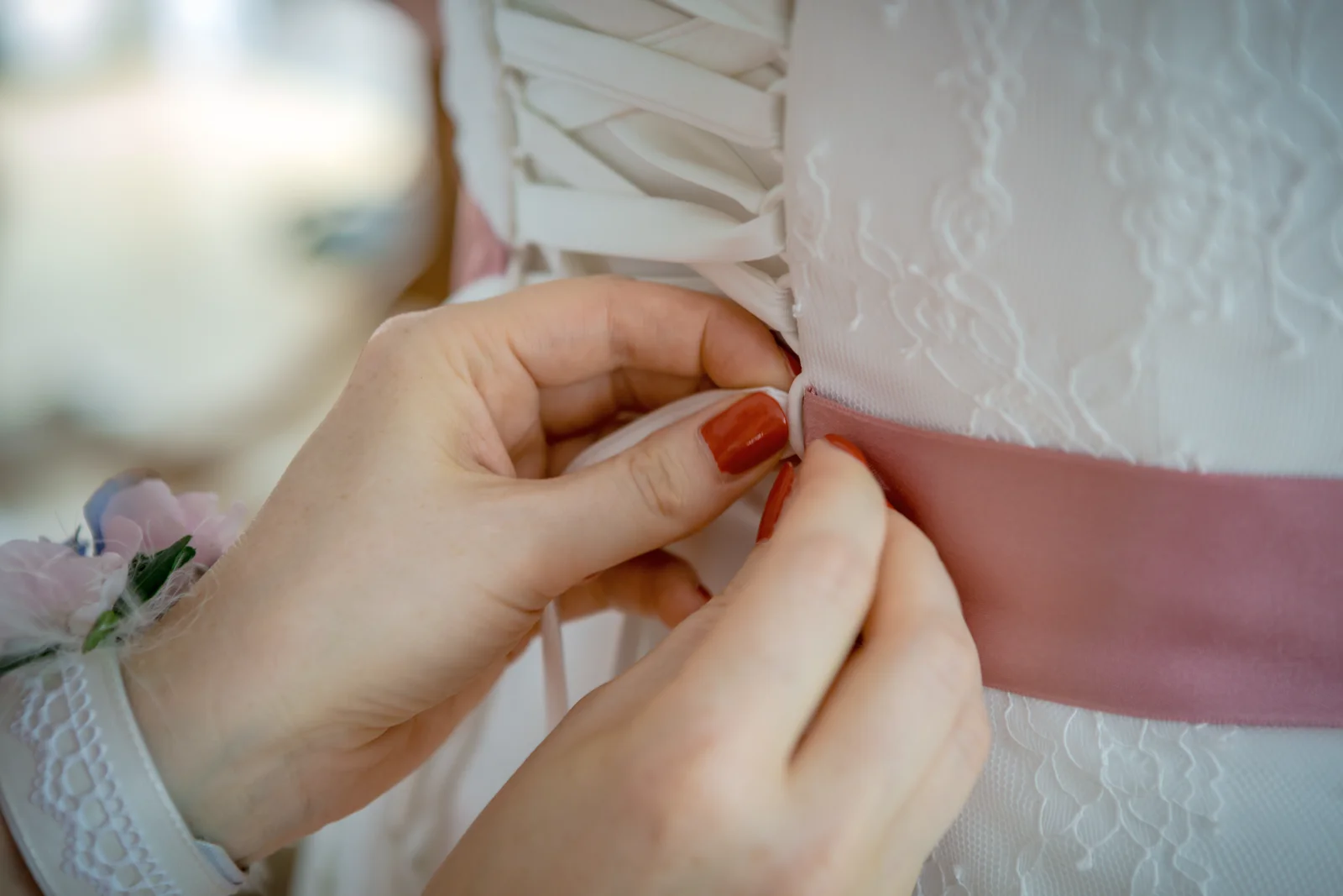Das rosa Band am Brautkleid wird befestigt – Hochzeit von Nadja und Steve in Elbe-Parey
