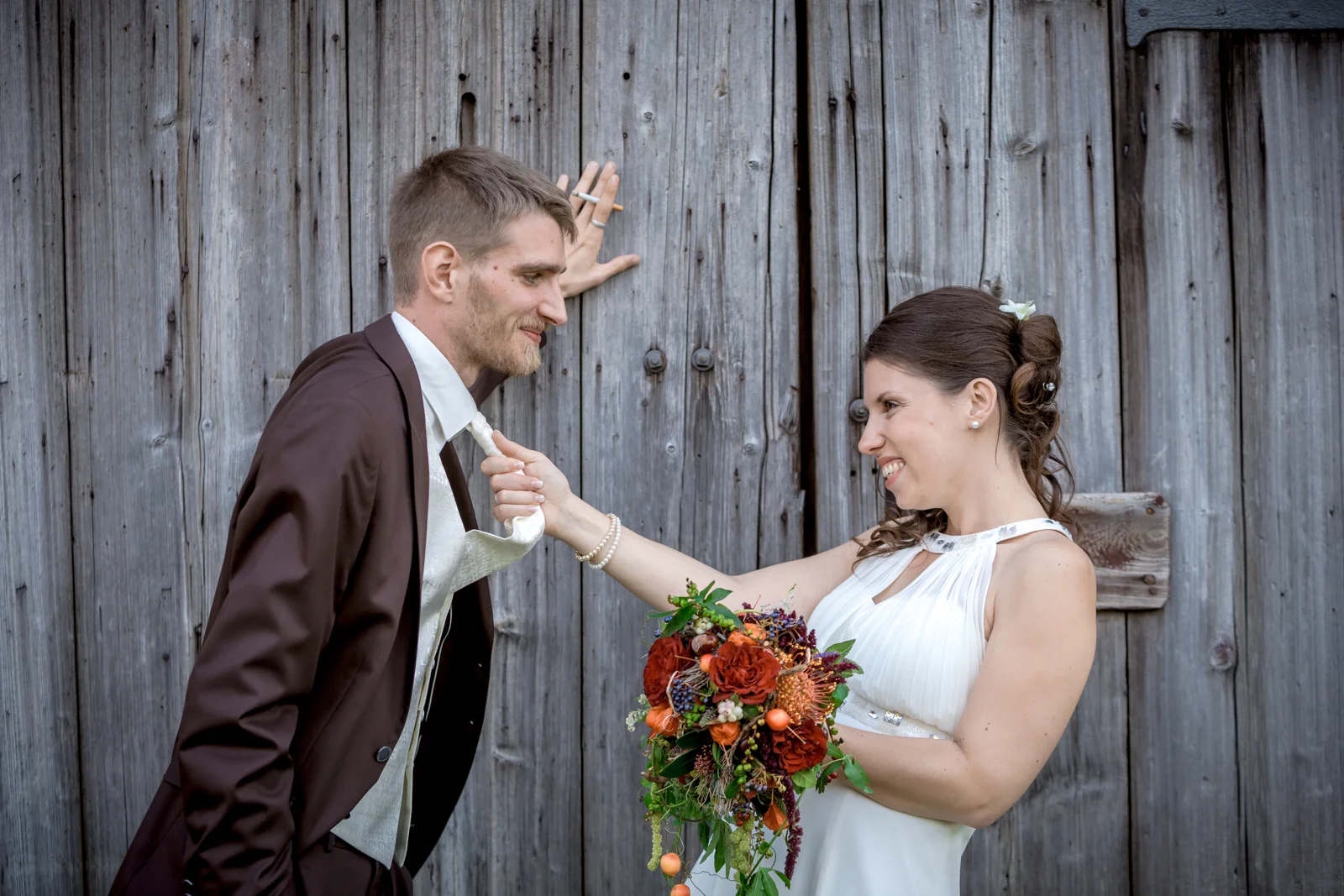Ein spielerischer Moment am Holztor – Hochzeit von Daniel und Katharina in Emskirchen – Schloss Brunn