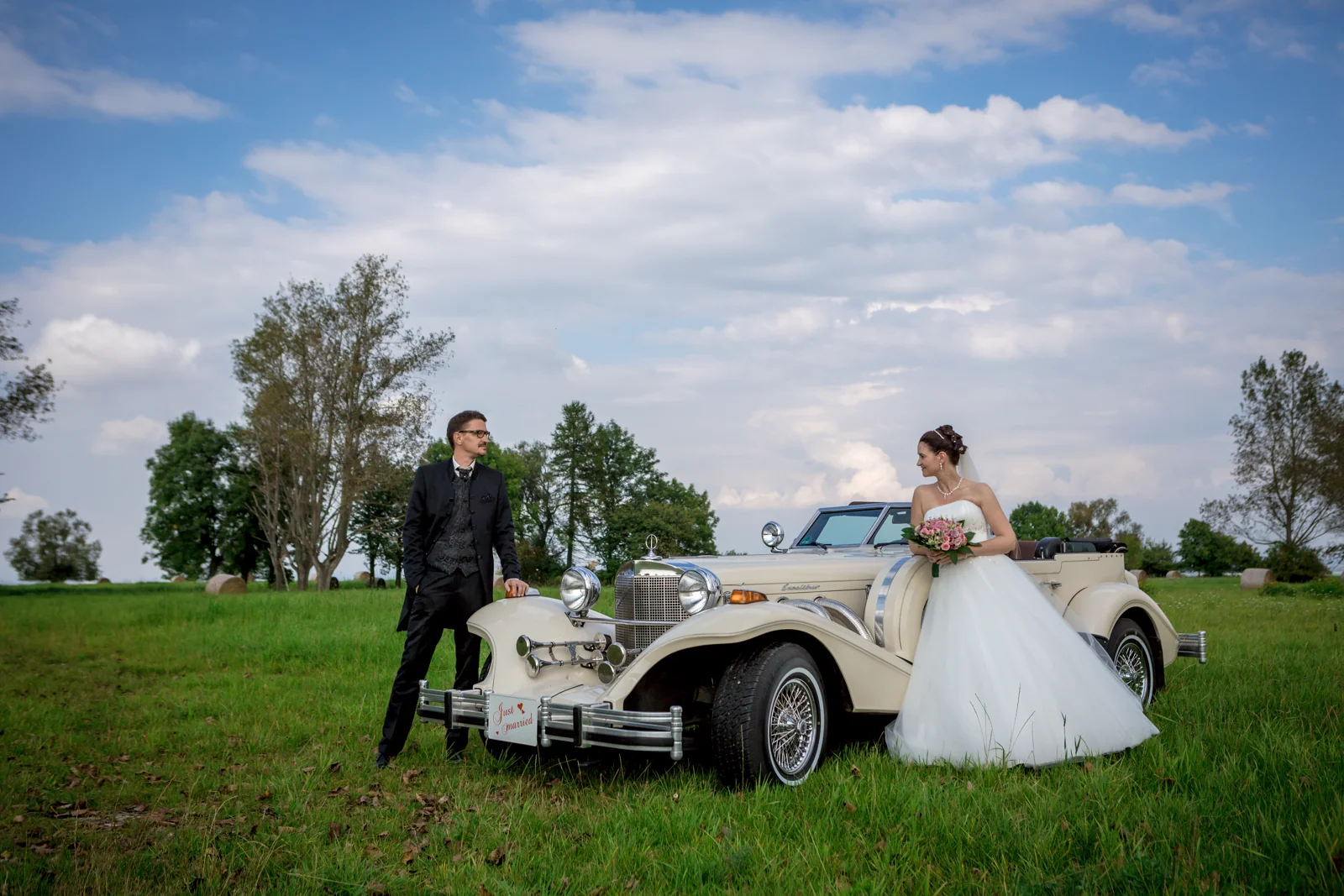 Das Brautpaar mit dem Hochzeitsauto auf der Wiese – Hochzeitsreportage von Matthias und Kerstin