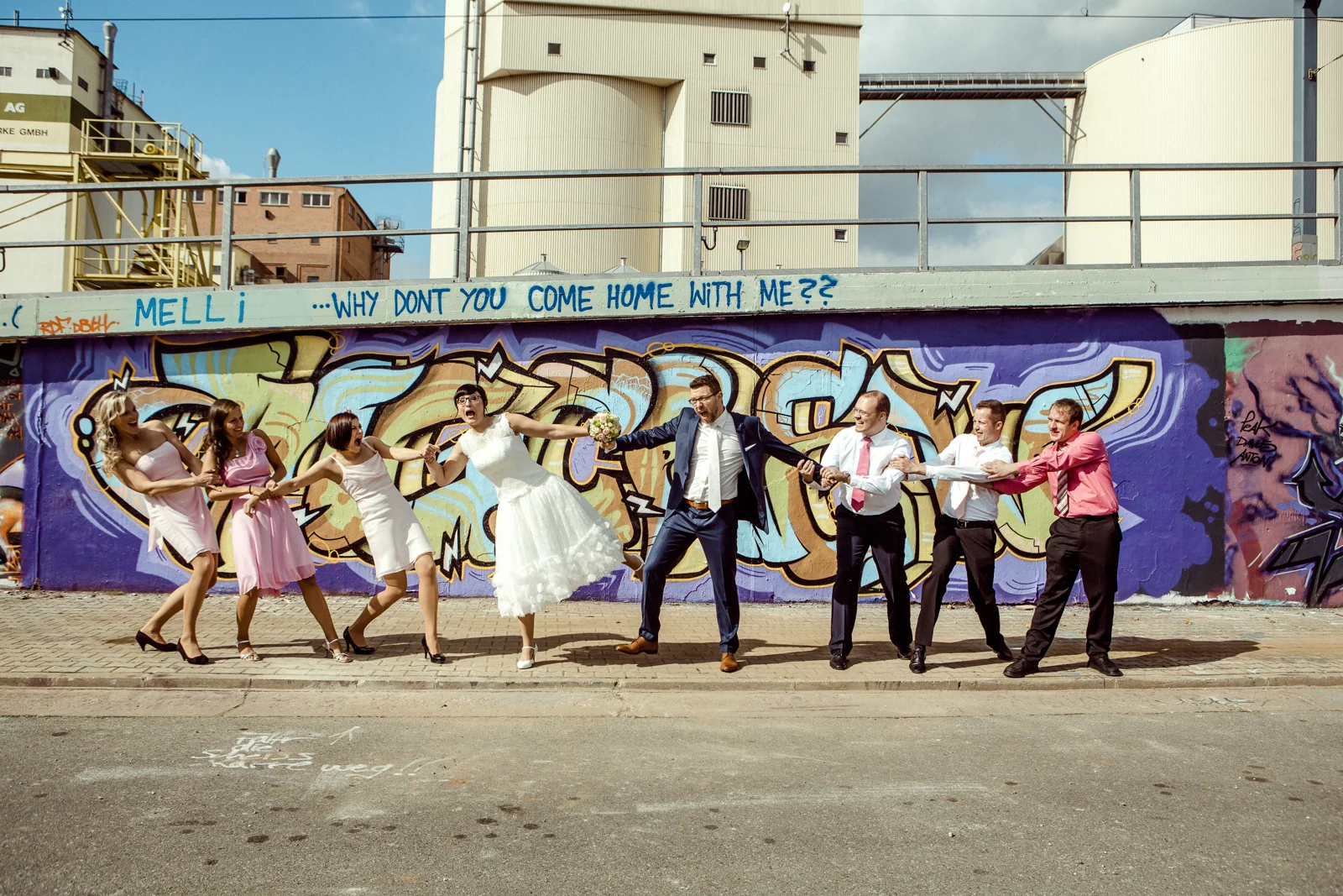 Die Hochzeitsgesellschaft springt gemeinsam vor der Graffitiwand – Hochzeitsreportage von Melanie und André