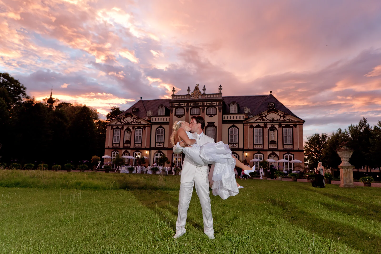 Lars trägt Sandra vor der Schlosskulisse – Hochzeitsreportage von Sandra und Lars