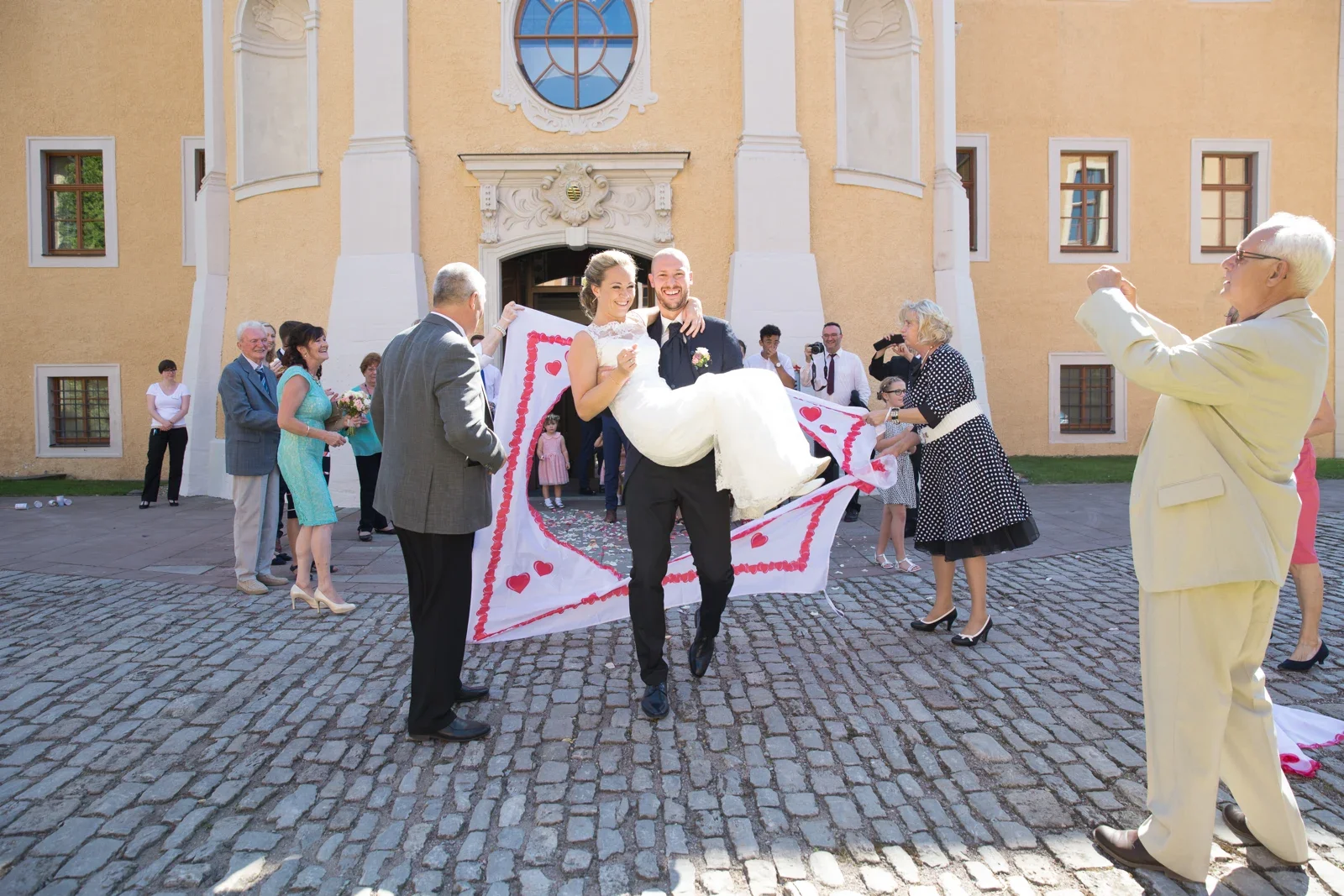 David trägt Caro durch das ausgeschnittene Herz – Hochzeit von Caro und David auf Schloss Ettersburg und in Blankenhain