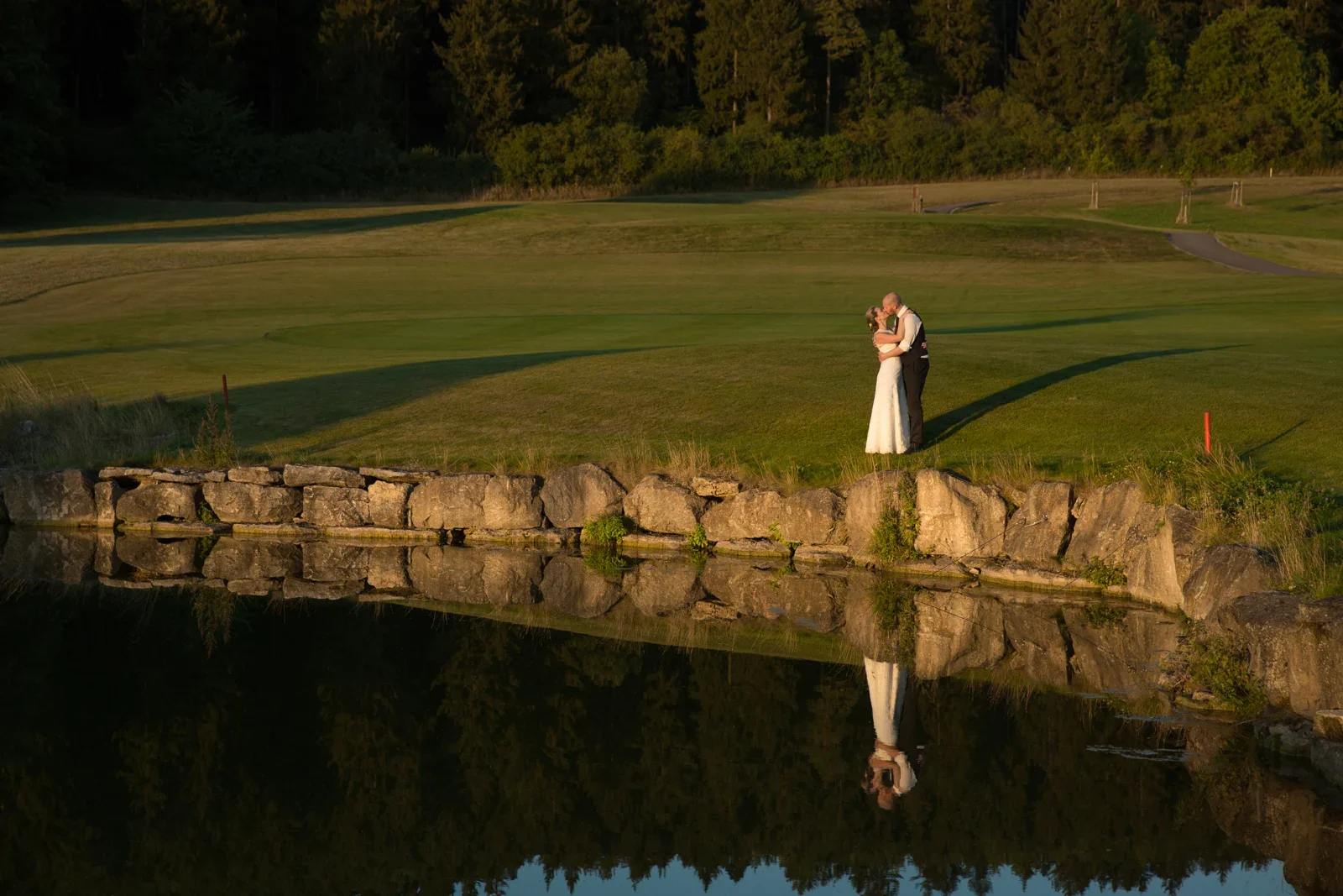 Caro und David spiegeln sich am Wasser des Golfplatzes – Hochzeit von Caro und David auf Schloss Ettersburg und in Blankenhain