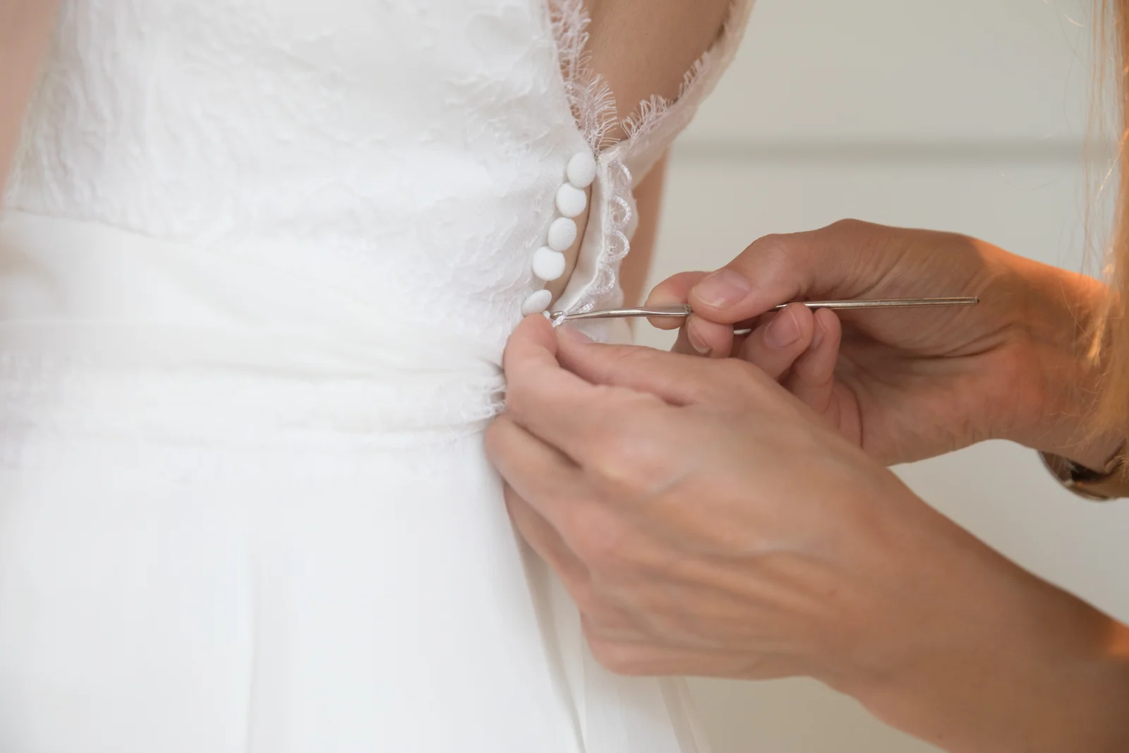 Die Knöpfe am Brautkleid werden geschlossen – Hochzeit von Hannah und Martin in Rellingen und Wedel