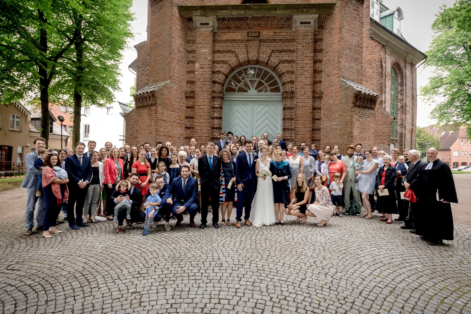 Gemeinsames Gruppenbild vor der Rellinger Kirche – Hochzeit von Hannah und Martin in Rellingen und Wedel