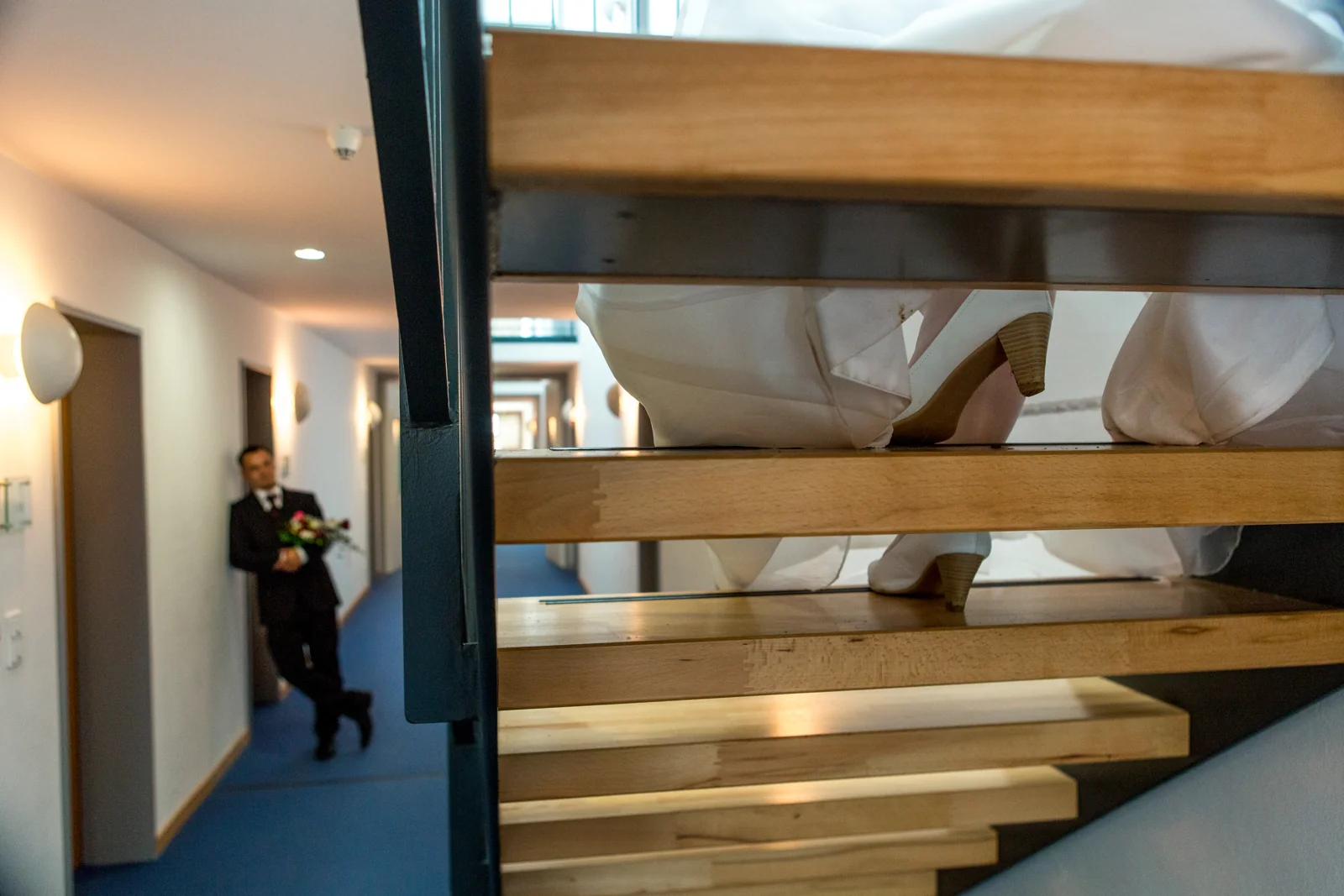 Brautschuhe auf der Treppe und André im Hintergrund – Hochzeitsreportage von Sandra und André