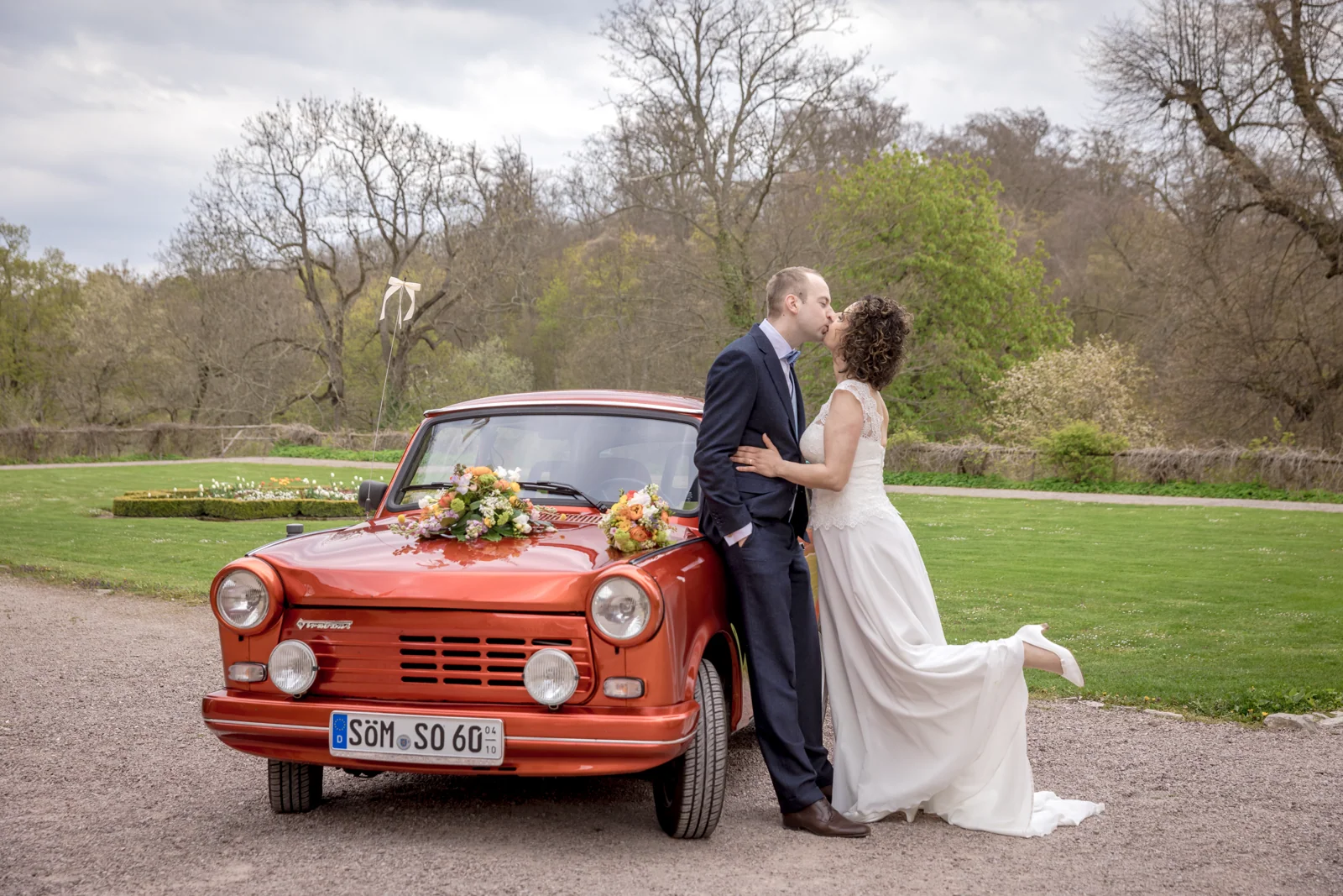Ein Kuss am orangefarbenen Hochzeitsauto – Hochzeitsreportage von Ines und Alexander