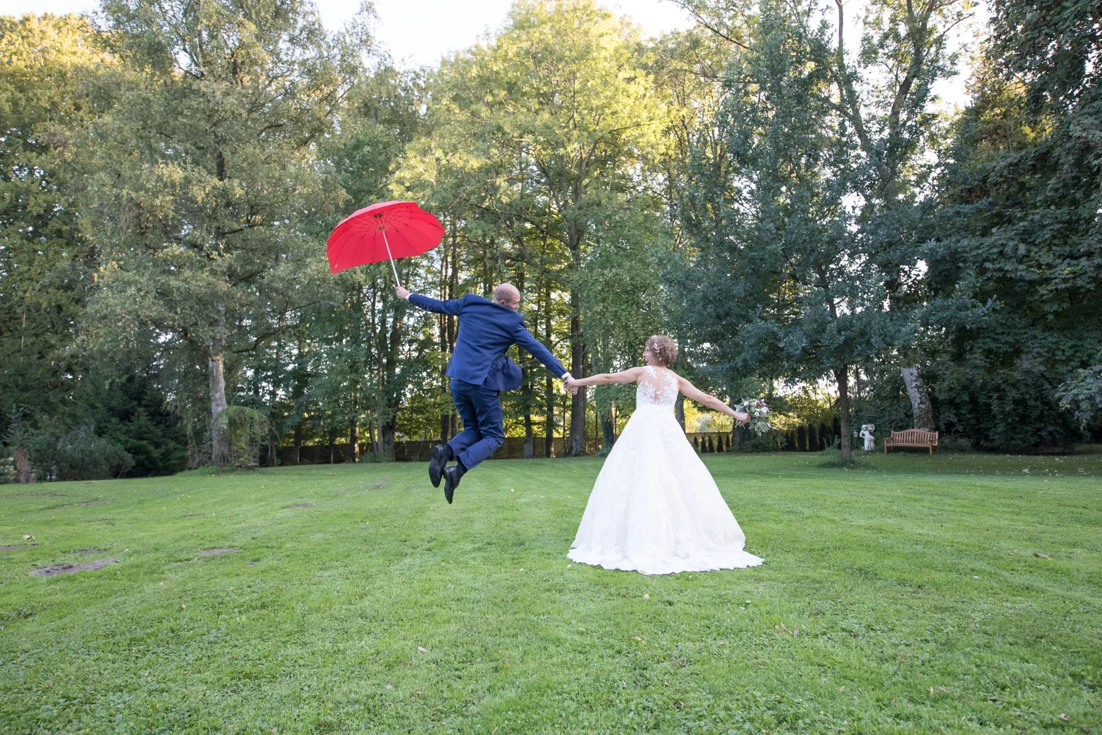 Ein Sprung mit rotem Schirm im Schlosspark – Hochzeit von Ann-Kathrin und Marko auf Schloss Oberndorf