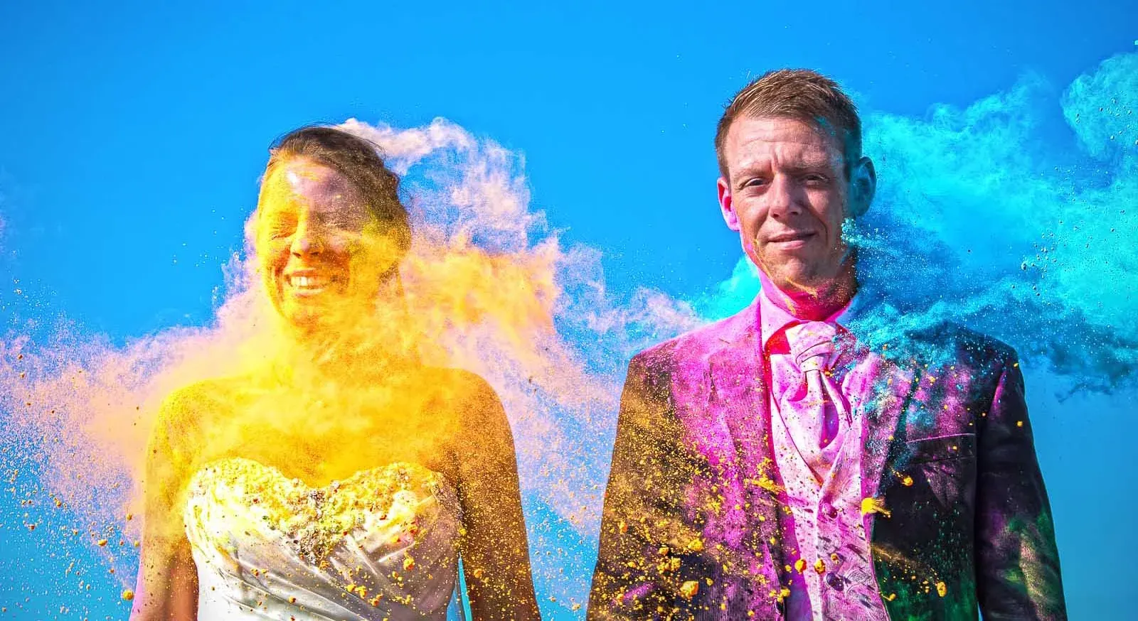 Hochzeitspaar umgeben von leuchtendem Farbpulver Hochzeitspaar umgeben von leuchtendem Farbpulver