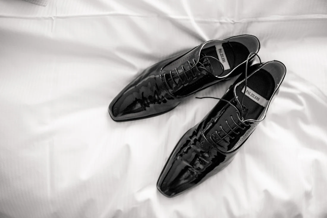 Schwarze Schuhe des Bräutigams auf hellem Stoff
