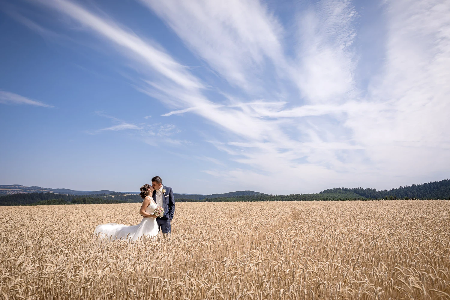 Brautpaar auf einem Feld unter weitem Sommerhimmel