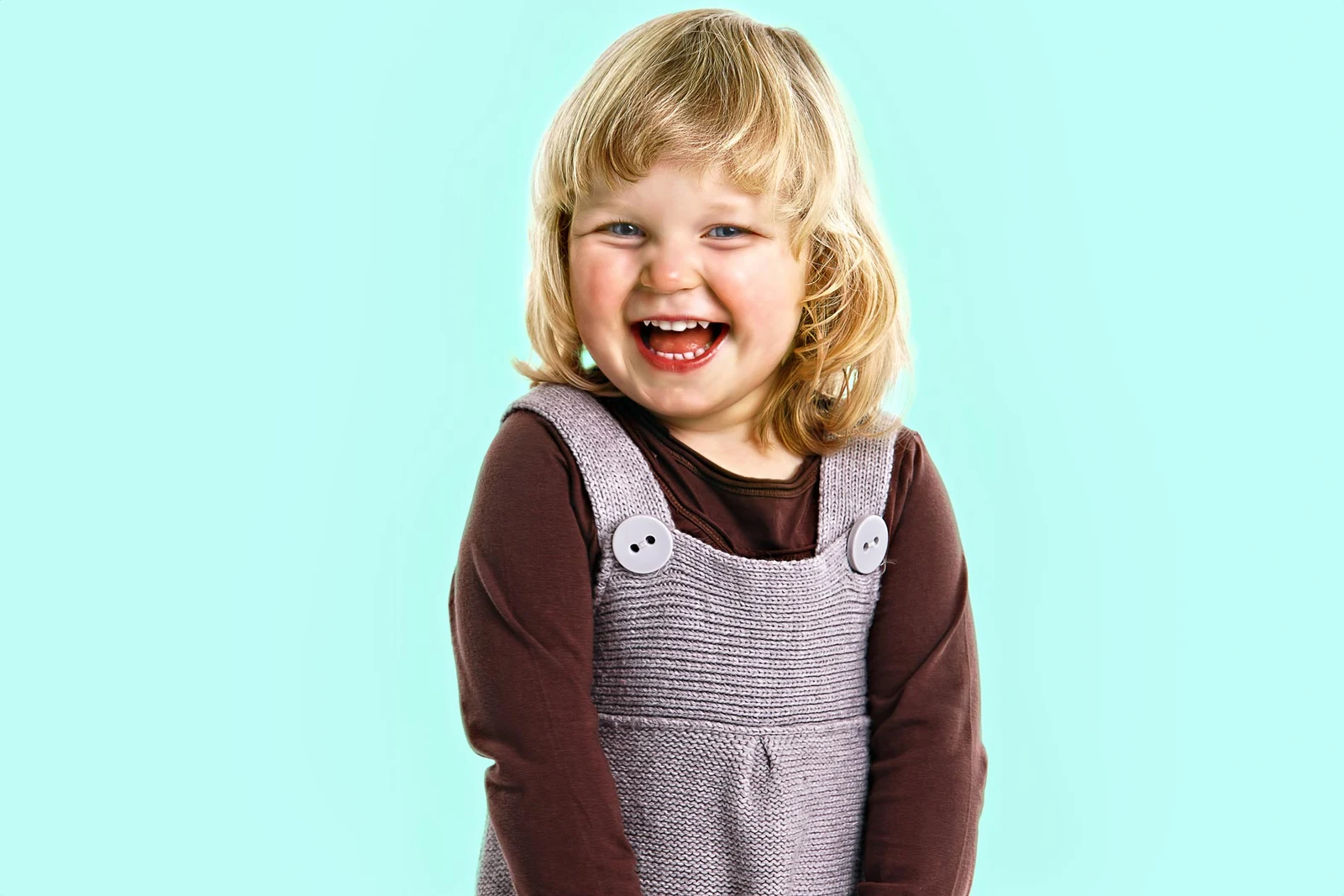 Lachendes Kind vor hellblauem Hintergrund im Fotostudio