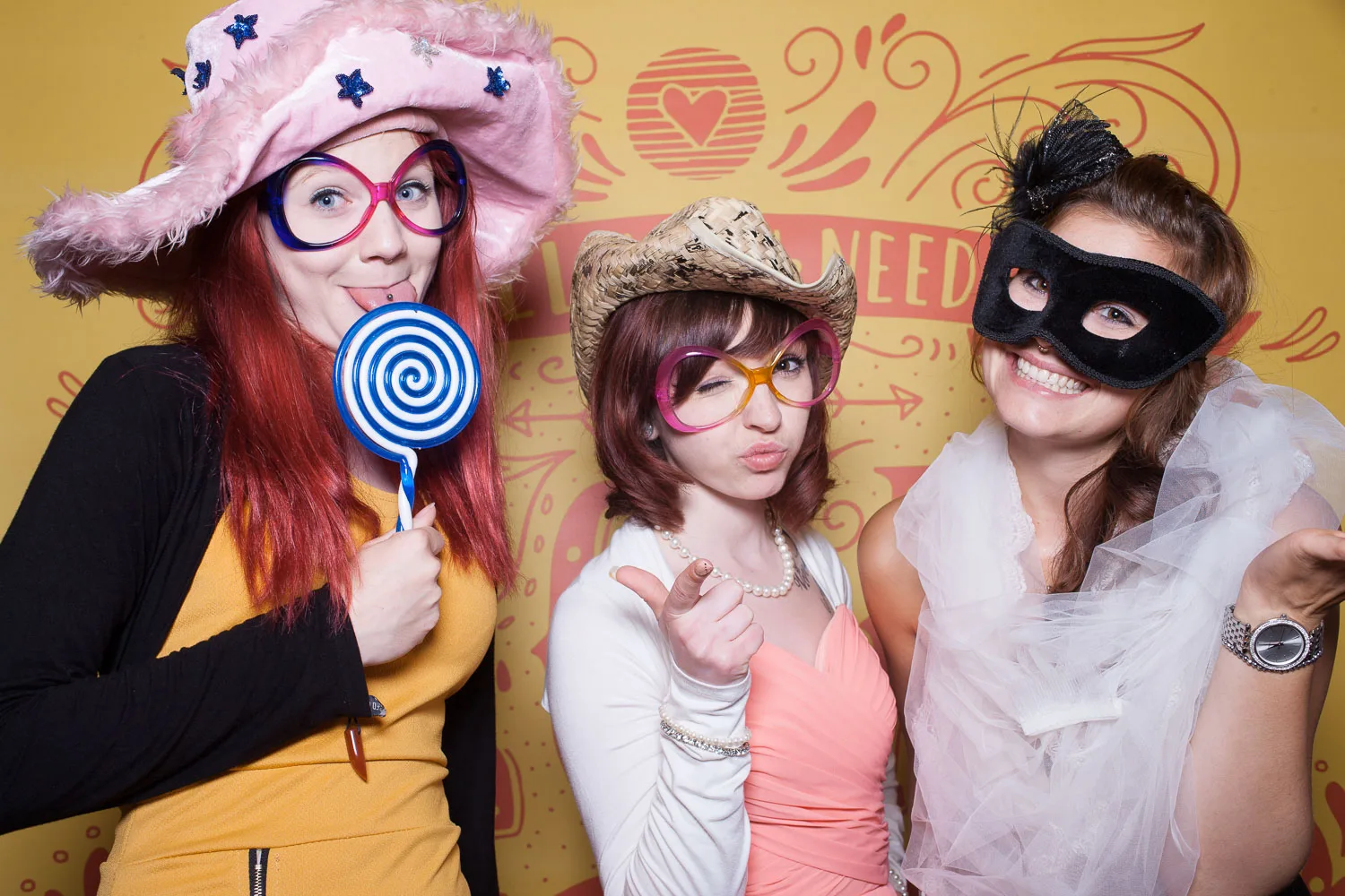 Drei Gäste mit rosa Hut, Maske und Lutscher-Requisite – Beispiel aus der Fotobox-Galerie von Delf Zeh