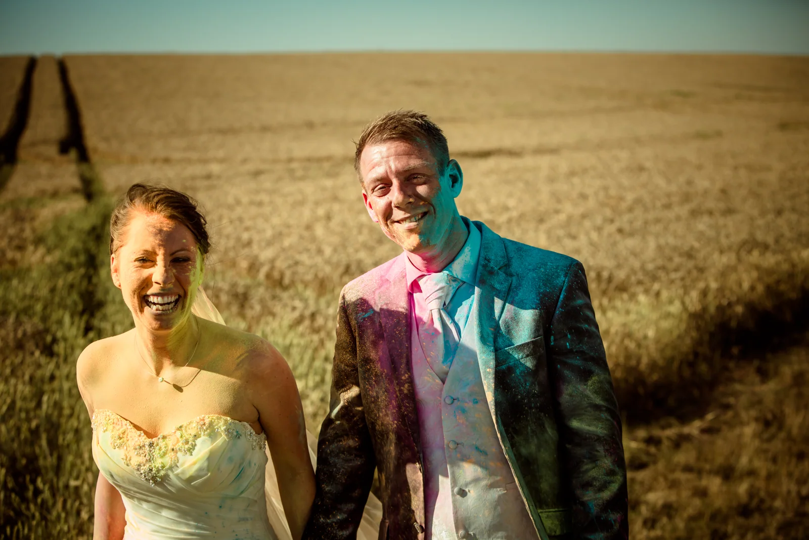 Das Brautpaar lacht nach der Farbpulveraktion – Trash the Dress mit Sabrina und Jan
