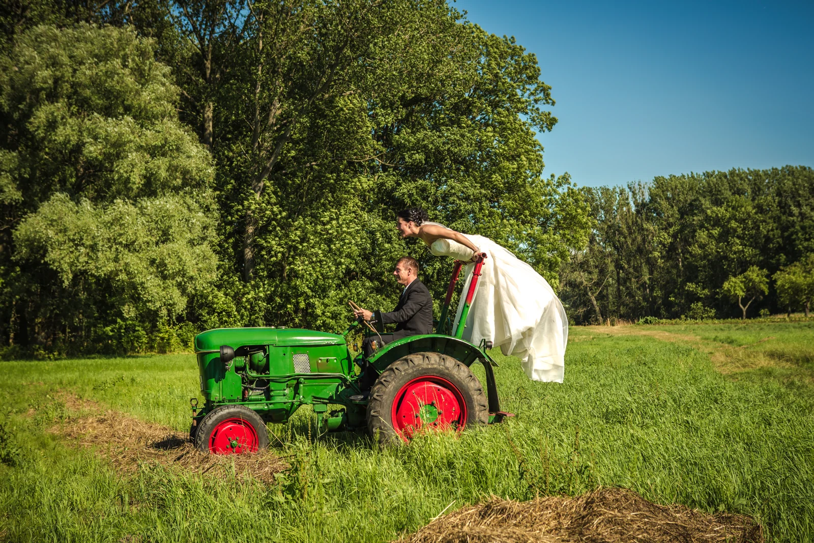 Sabrina lehnt sich über den grünen Traktor – Trash the Dress mit Sabrina und Jan