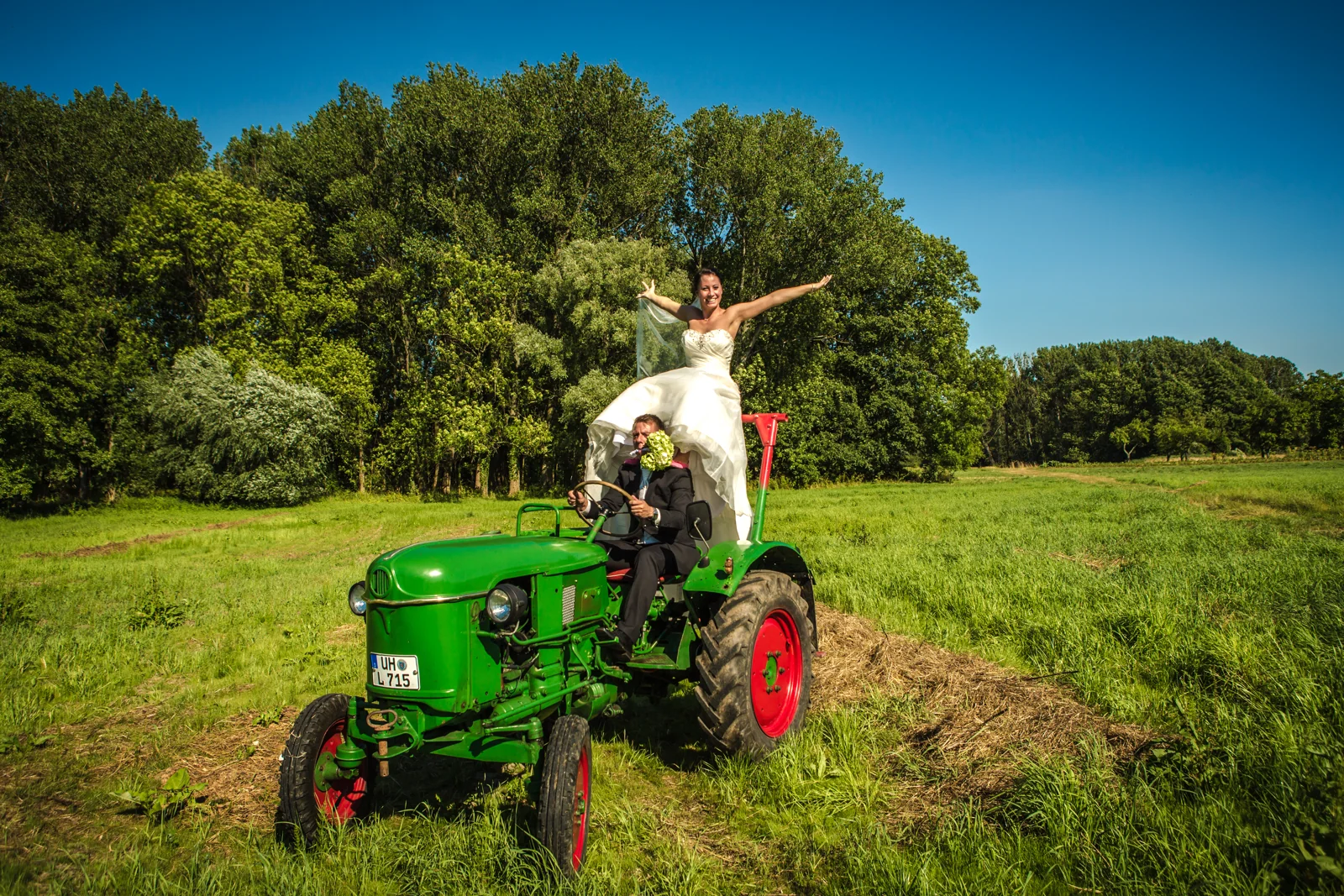 Sabrina mit ausgebreiteten Armen vor dem Traktor – Trash the Dress mit Sabrina und Jan
