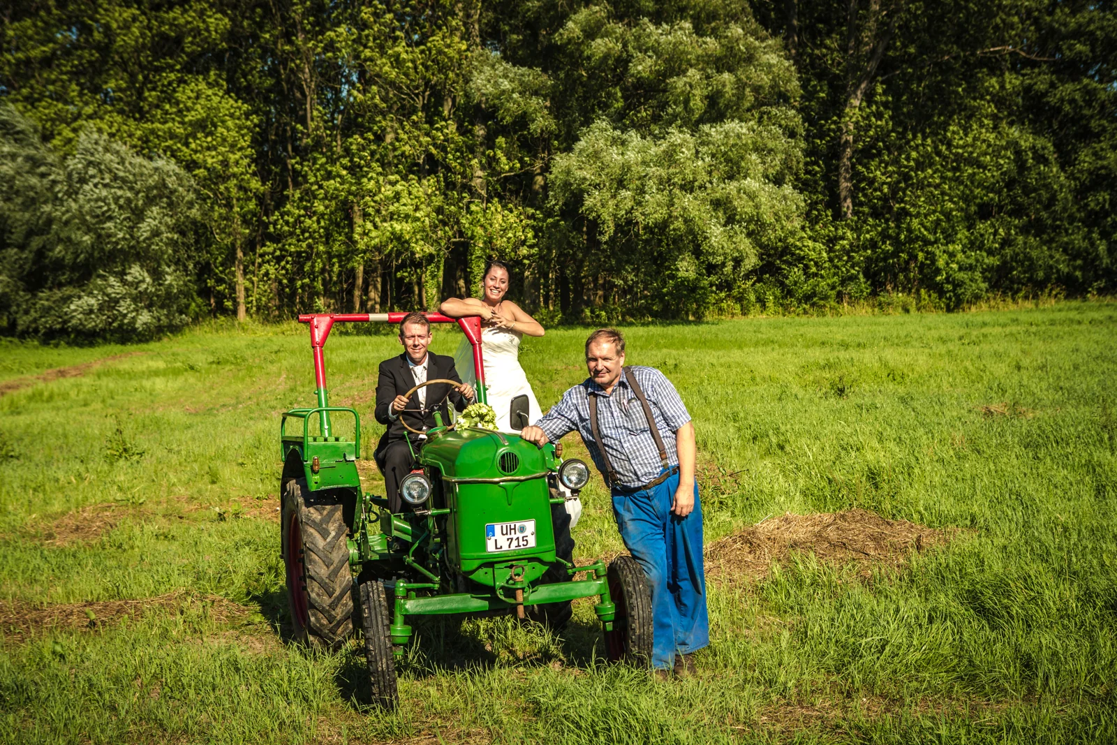 Das Brautpaar mit einem Helfer am Traktor – Trash the Dress mit Sabrina und Jan