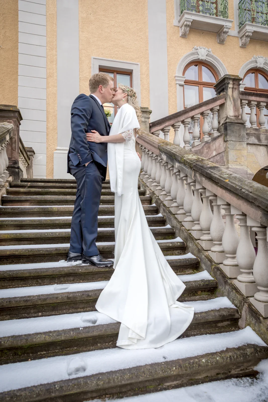 Ein Paarbild auf der Schlosstreppe – Winterhochzeit von Anika und Marcus auf Schloss Ettersburg und in Weimar